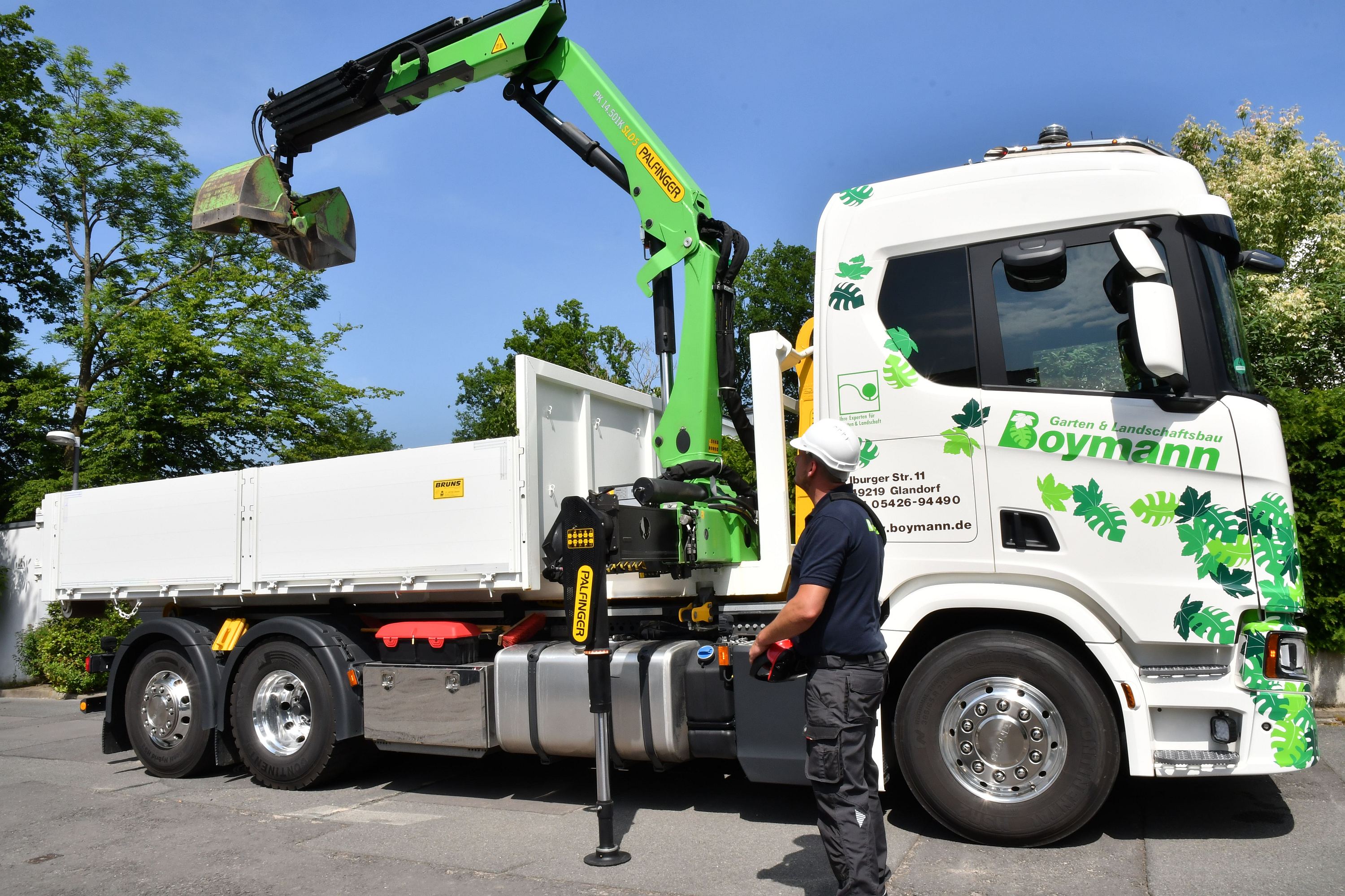 Palfinger - Boymann - DSC_6825 - Der Kranarm reckt sich über die grüne Hecke.jpg